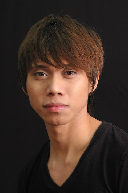 Selective closeup shot of a male with bangs and black shirt on black