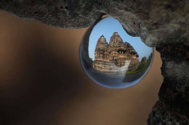 Selective closeup shot of the reflection of temple in Orcha, India in glass ball hanging from a rock