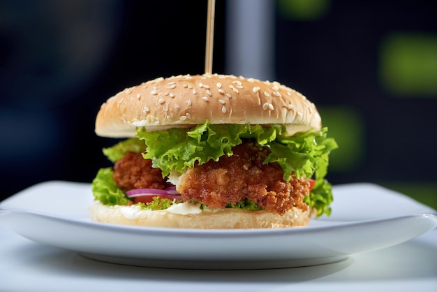 Foto gratuita messa a fuoco selettiva del grande hamburger cotto al bar che rimane sul piatto