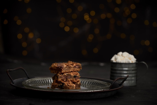 Selective focus closeup of cookies on a glass plate on the table with a cup of mallows on the side