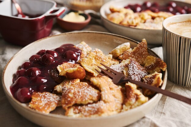 Selective focus closeup shot of delicious fluffy pancakes with cherry and powdered sugar