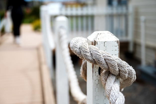 Free photo selective focus closeup shot of a rope tied on a wooden post from an old lighthouse