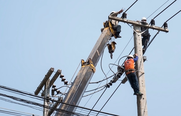 Foto gratuita il fuoco selettivo degli elettricisti sta riparando la linea di trasmissione di energia su un palo dell'elettricità