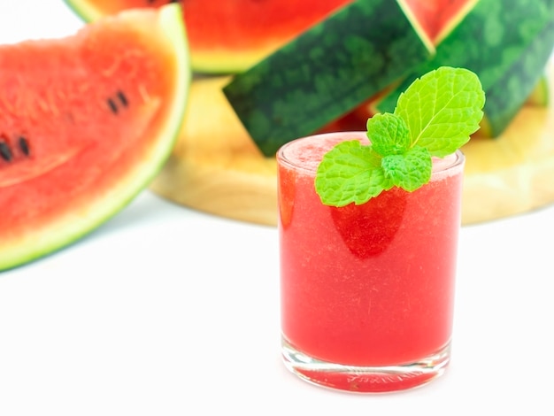 Selective focus of fresh watermelon in a glass with mint decoration on white background