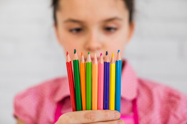 Selective focus of a girl looking at colorful pencils in hand