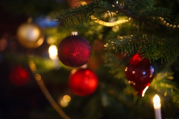 Selective focus of red baubles on green Christmas tree