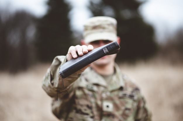 カメラの近くに聖書を持っているアメリカの兵士の選択的なフォーカスショット