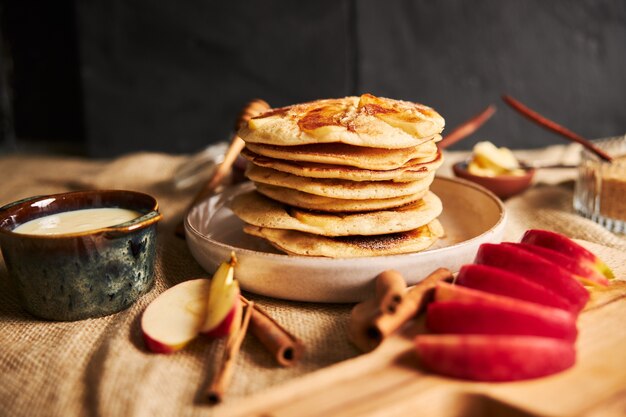 Selective focus shot of apple pancakes with apples and other ingredients on the table