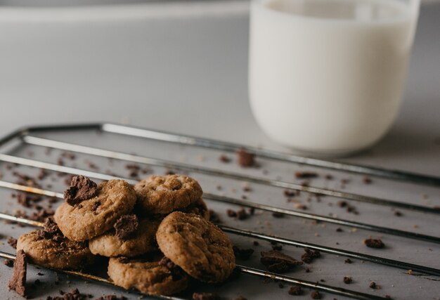 Selective focus shot of the baking grid with delicious round chocolate cookies and a cup of milk