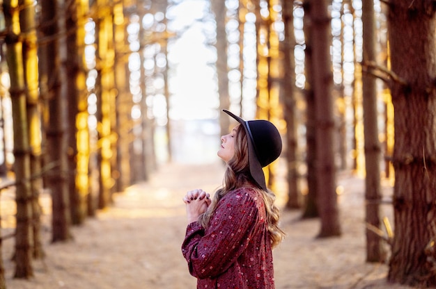 Foto gratuita messa a fuoco selettiva di una bellissima giovane donna che prega in una foresta
