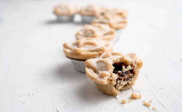 Selective focus shot of a bitten mince pie on the mince pies line