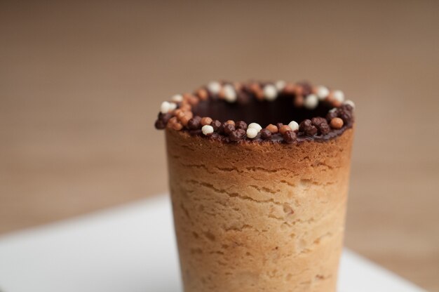 Selective focus shot of a cup made of biscuit on a wooden surface