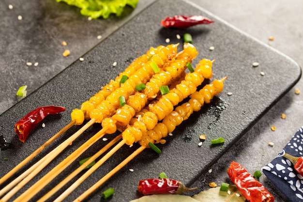 Selective focus shot of delicious corn on wooden skewers seasoned with various spices