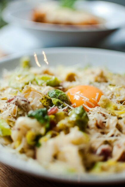 Selective focus shot of delicious pasta with cheese vegetables and egg