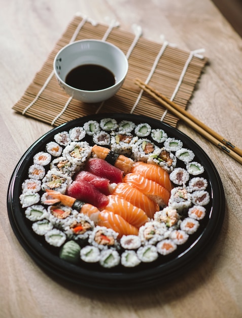 Foto gratuita colpo di messa a fuoco selettiva dei deliziosi involtini di sushi serviti in un piatto rotondo nero