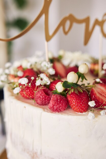 赤いベリー、花、ケーキトッパーとおいしい白いウエディングケーキの選択的なフォーカスショット