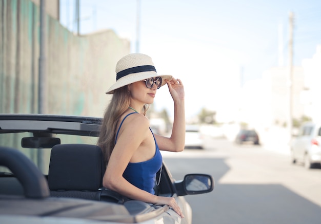 Selective focus shot of female on the driver seat of a white convertible sports car