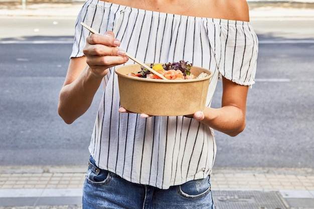 Free photo selective focus shot of female holding chopsticks with organic carton bowl