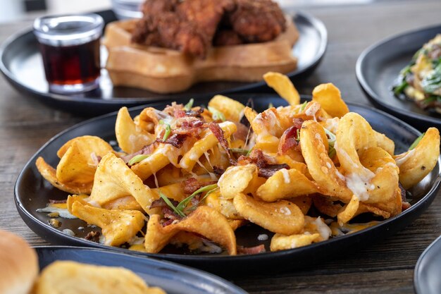 Selective focus shot of French fries with melted cheese and sliced sausage on a wooden table