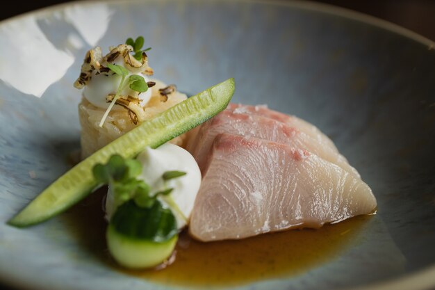 Селективный снимок свежего салата с нарезанной королевской рыбой, огурцом и рисом