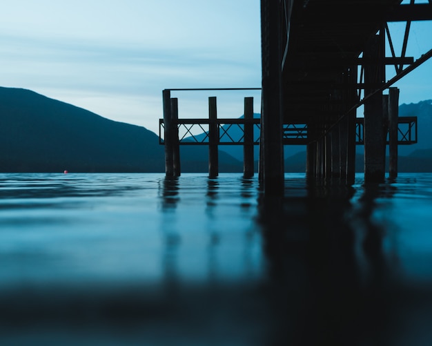 Selective focus shot from of a pathway over the water with mountains in the distance