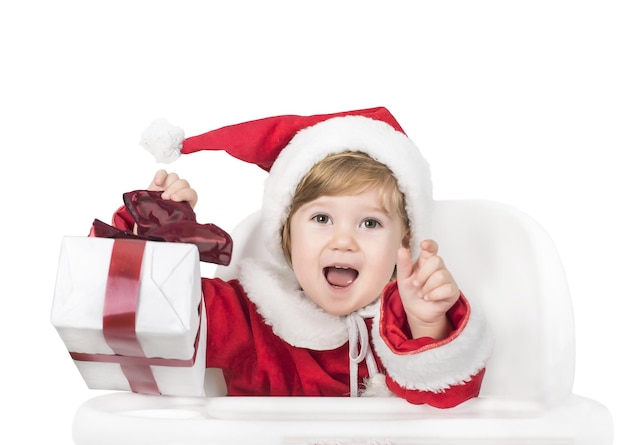Selective focus shot of a happy little girl dressed as Santa Claus opening a gift