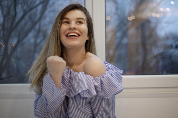 Selective focus shot of a happy woman pumping her fist with a blurred space