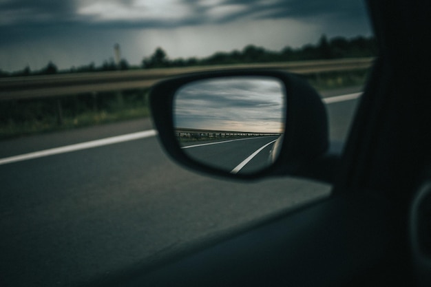 Colpo di messa a fuoco selettiva della riflessione dell'autostrada su uno specchietto laterale dell'auto