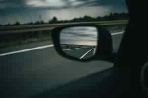 Foto gratuita colpo di messa a fuoco selettiva della riflessione dell'autostrada su uno specchietto laterale dell'auto