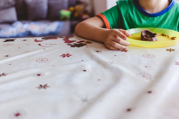 テーブルの上でチョコレートを食べる子供の選択的なフォーカスショット