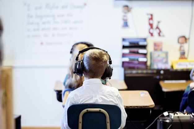 교실에 앉아 헤드폰을 착용하는 아이의 선택적 초점 샷