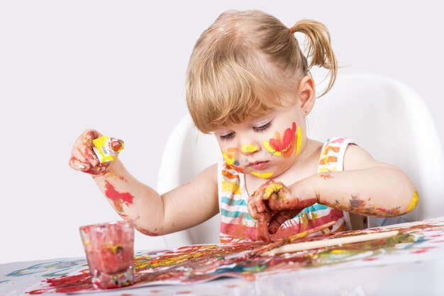 Selective focus shot of a little girl painting and playing