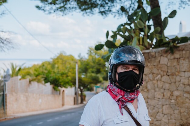 Selective focus shot of a male in a black medical mask and motorcycle helmet