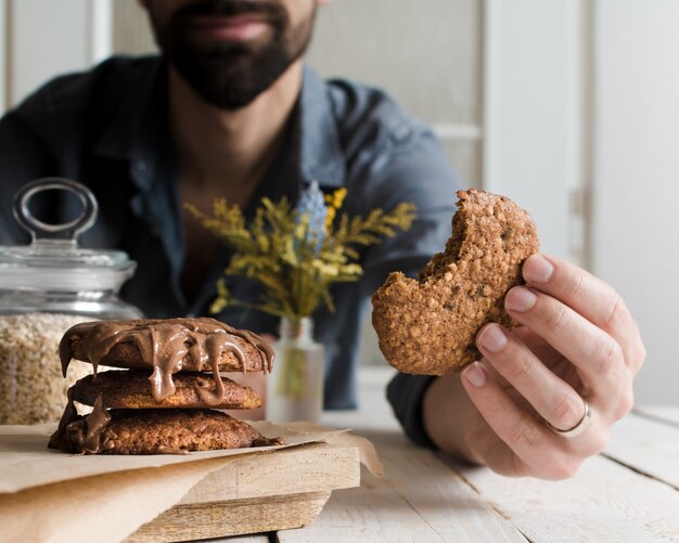 Selective focus shot of a male eating delicious chocolate cookies