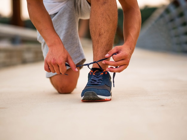 Selective focus shot of a male tying his shoelaces at outdoors
