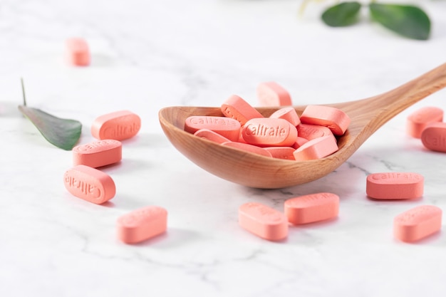 Selective focus shot of many calcium tablets Caltrate in a wooden spoon