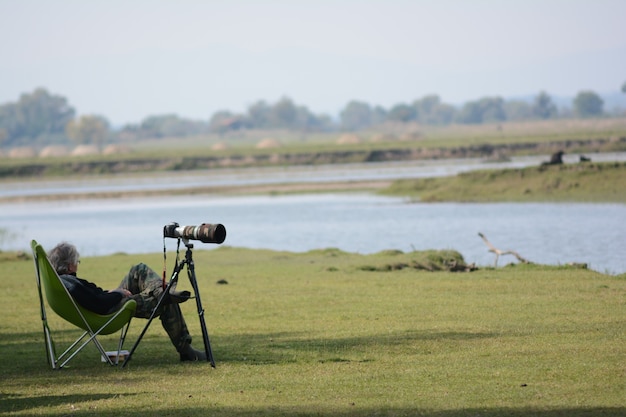 Selective focus shot of an old man resting on a folding chair with his DSLR camera on the side