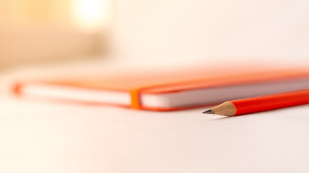 Selective focus shot of a pencil and a notebook on a white table