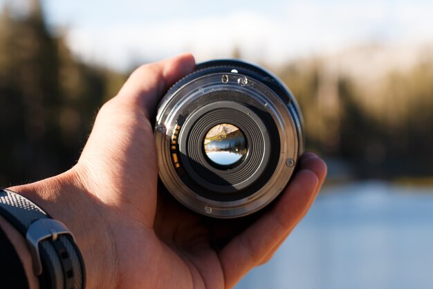 Selective focus shot of a person holding a camera lens