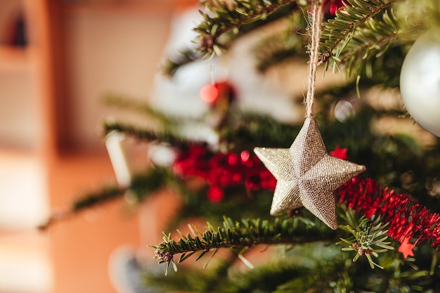 Selective focus shot of star ornament hanging on Christmas tree