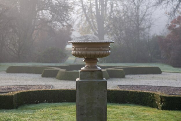 Selective focus shot of a stone pot on a pedestal in a park