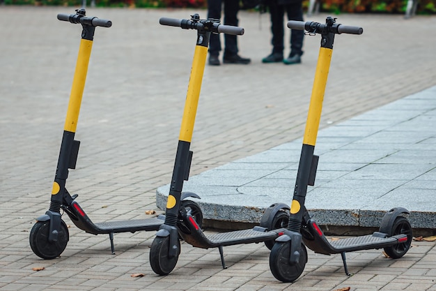 Foto gratuita messa a fuoco selettiva di tre scooter elettrici sul marciapiede