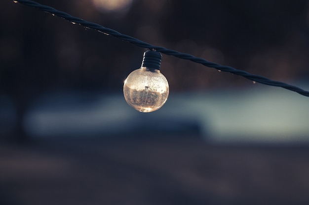 Selective focus shot of a turned-off lightbulb on a string