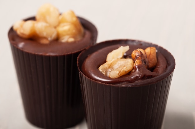 Selective focus shot of two chocolates with nuts as topping with a white background