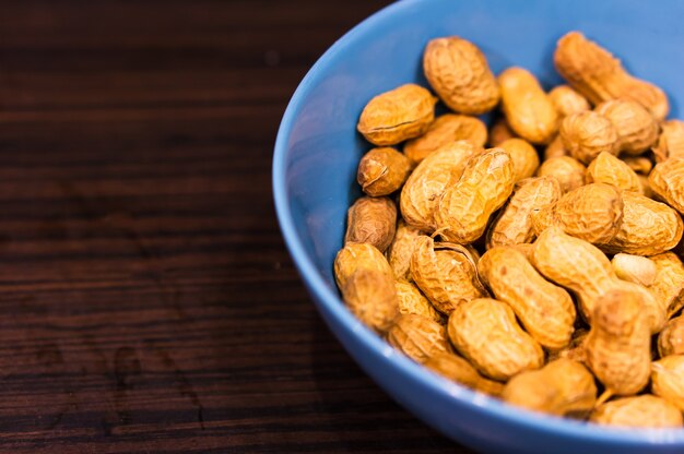 Selective focus shot of a vibrant blue bowl of peanuts