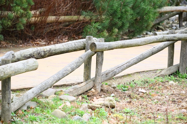 Selective focus shot of a wooden fence near a pathway at the park