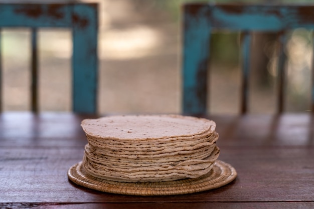 Selective focus shot of a woven plate filled with fresh homemade bread on a wooden table