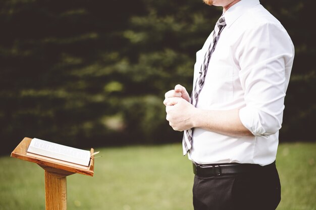 Selective focus shot of a young male standing in front of a wooden church stand