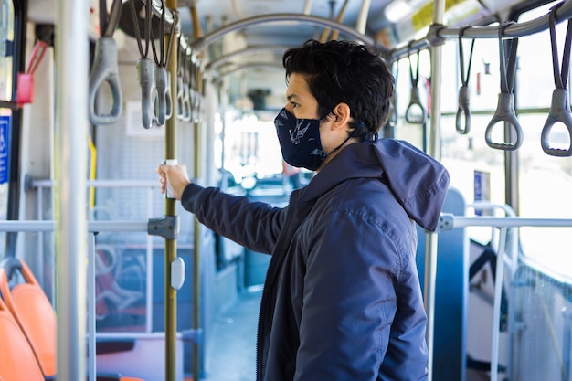 Selective focus shot of a young man with a mask holding onto the railing