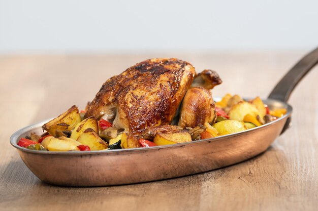 Selective focus of a spit-roasted chicken with potatoes